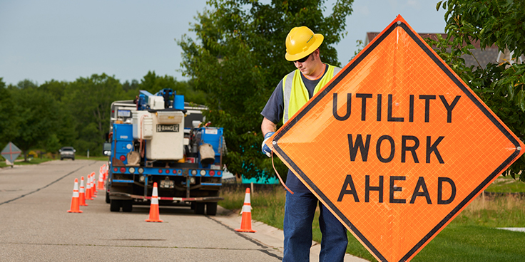 worker putting up utility caution sign